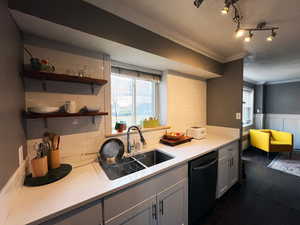 Kitchen with plenty of natural light, black dishwasher, ornamental molding, and a wainscoted wall