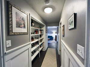 Corridor featuring a textured ceiling and wood finished floors