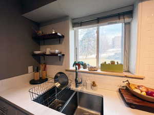 Kitchen with light countertops, tasteful backsplash, open shelves, and a sink