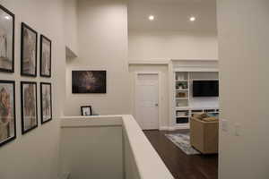 Hallway featuring built in shelves and dark hardwood / wood-style floors