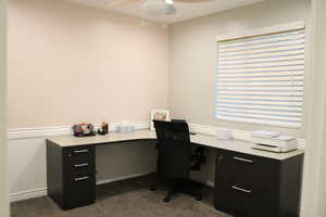 Home office featuring dark colored carpet and ceiling fan