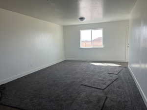 Spare room featuring baseboards and dark carpet
