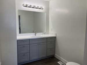 Bathroom featuring wood finished floors, vanity, baseboards, and visible vents
