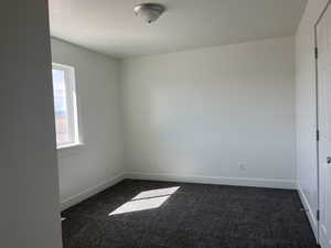 Spare room featuring baseboards and dark colored carpet