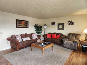 Living area featuring a textured ceiling, wood finished floors, and baseboards