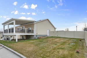 View of side of home featuring a deck, a yard, a fenced backyard, and a gate