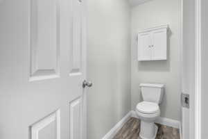 Bathroom featuring baseboards, toilet, and wood finished floors