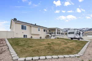 Rear view of property featuring stairs, fence, and a yard