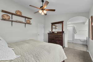 Primary Bedroom with arched walkways, carpet floors, a ceiling fan