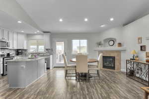 Dining room with a tiled fireplace, baseboards, dark wood-style flooring, and recessed lighting