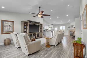 Living room  a tile fireplace, ceiling fan, light wood-style floors, and recessed lighting