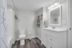 Bathroom with large vanity, toilet, and wood finished floors