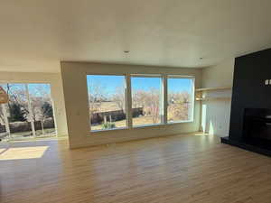 Unfurnished living room featuring a textured ceiling, a wealth of natural light, a fireplace, and light wood-style flooring