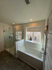 Full bath featuring a textured ceiling, a garden tub, recessed lighting, visible vents, and a stall shower