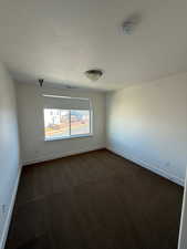 Spare room featuring a textured ceiling, dark carpet, visible vents, and baseboards