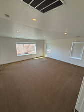 Empty room with recessed lighting, visible vents, dark carpet, a textured ceiling, and baseboards