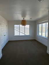 Unfurnished bedroom featuring a textured ceiling, dark colored carpet, visible vents, and baseboards