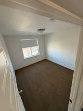 Unfurnished room with dark carpet, a textured ceiling, and baseboards