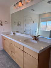 Bathroom with double vanity, a sink, and visible vents