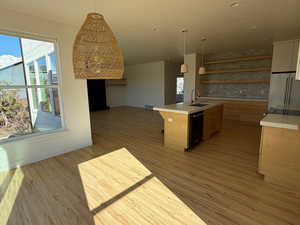 Kitchen featuring a sink, open floor plan, light countertops, light wood-type flooring, and dishwasher