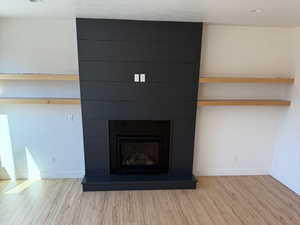 Details with a textured ceiling, a fireplace, wood finished floors, and baseboards