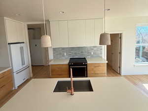 Kitchen featuring a sink, high end fridge, light countertops, backsplash, and modern cabinets