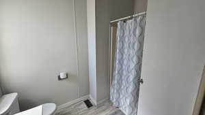 Full bath in suite with baseboards, visible vents, toilet, and a shower with curtain