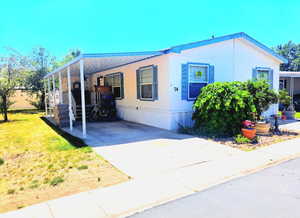 View of front of home featuring a carport, a front lawn, and driveway