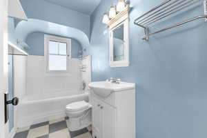 Full bath with washtub / shower combination, vanity, toilet, and tile patterned floors