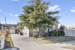 Obstructed view of property featuring a garage, driveway, fence, and stucco siding