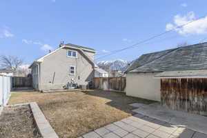 Back of house with cooling unit, a fenced backyard, a mountain view, and stucco siding