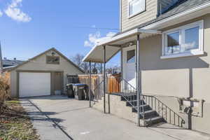 View of home's exterior with a detached garage, stucco siding, a shingled roof, concrete driveway, and fence