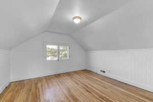 Additional living space featuring lofted ceiling, wood-type flooring, and visible vents