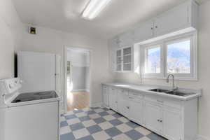 Kitchen with white appliances, a sink, white cabinetry, light countertops, and light floors