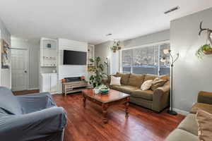 Living area with baseboards, visible vents, and wood finished floors