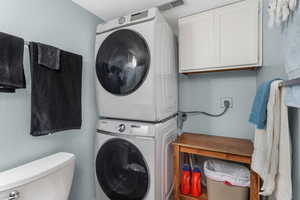 Clothes washing area with laundry area, stacked washing maching and dryer, and visible vents