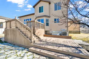 Rear view of house with stairway, cooling unit, a wooden deck, and stucco siding