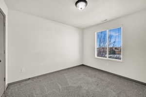 Carpeted empty room with visible vents, baseboards, and a textured ceiling