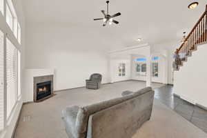 Tiled living room featuring plenty of natural light, stairs, visible vents, and a fireplace with flush hearth