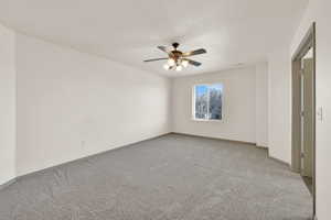 Interior space featuring a ceiling fan, light colored carpet, and baseboards