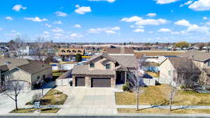 View of front of house featuring fence, a garage, a residential view, stone siding, and driveway