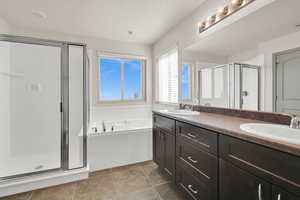 Bathroom with a bath, a stall shower, double vanity, and a sink