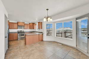 Kitchen with a notable chandelier, a peninsula, a sink, visible vents, and appliances with stainless steel finishes