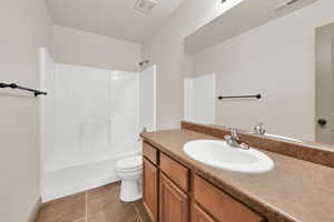 Full bathroom with washtub / shower combination, visible vents, vanity, and toilet