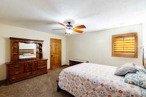 Bedroom featuring baseboards, visible vents, a ceiling fan, carpet, and a textured ceiling