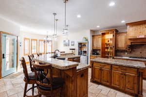 Kitchen with a large island, tasteful backsplash, recessed lighting, stone tile flooring, and a sink