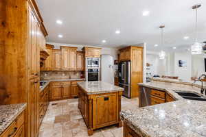 Kitchen featuring stone tile floors, appliances with stainless steel finishes, arched walkways, and a sink