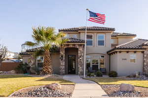 Mediterranean / spanish house with a tile roof, a front yard, and stucco siding