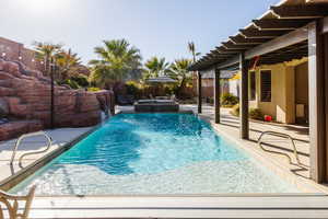 View of swimming pool featuring a pool with connected hot tub, a patio area, and fence