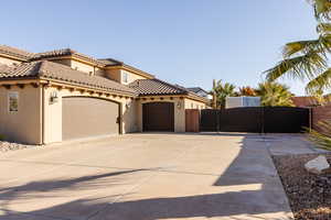 View of front of property featuring stucco siding, concrete driveway, an attached garage, a gate, and fence